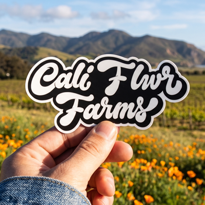 Cali Flwr logo sticker held in front of California hills and poppy fields